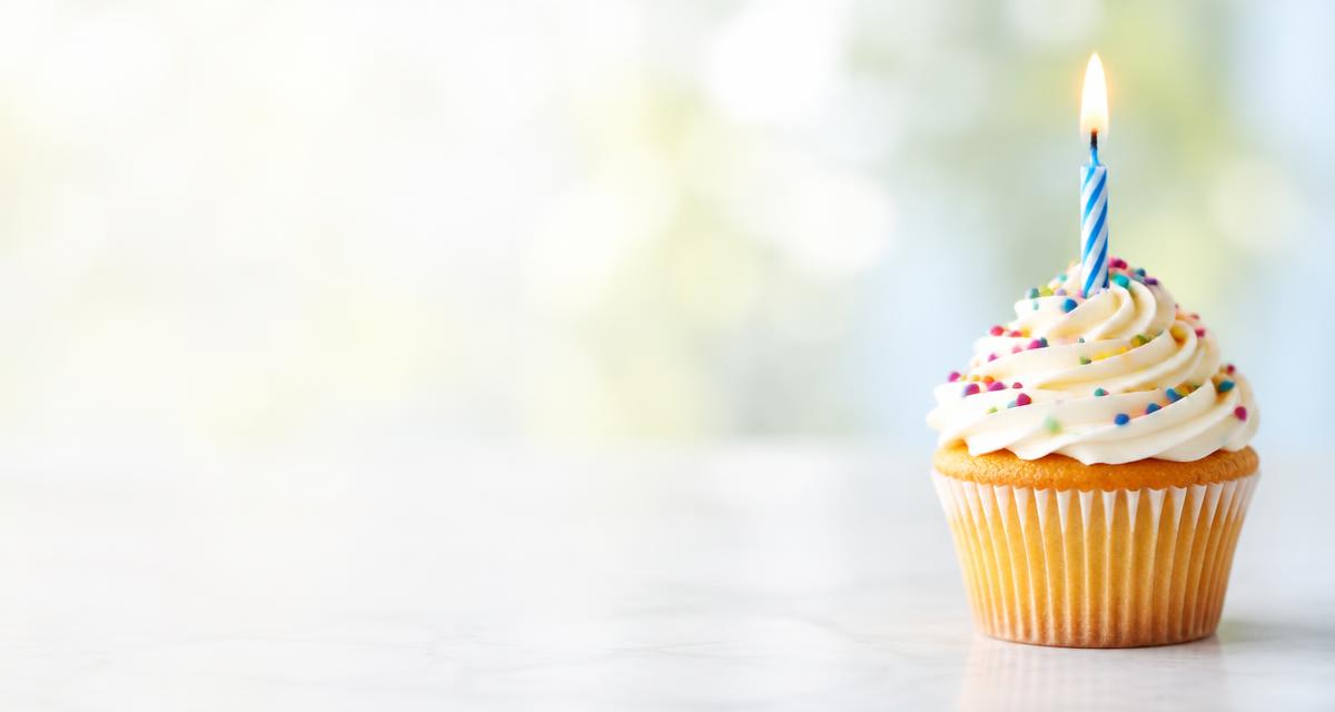 A frosted cupcake with one lit candle